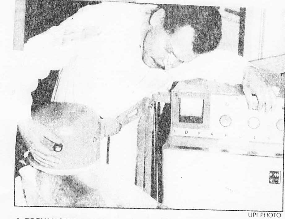 Technician administering an electrical charge to an injured cat in a spinal-cord repair test.